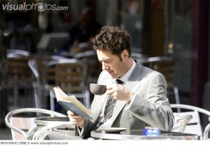 カフェで子＾ひーを読みながら読書する男性